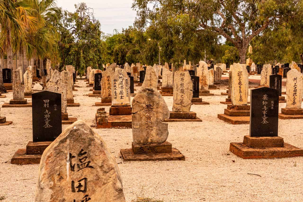 Grave headstones in a cemetery with Japanese script on the headstones